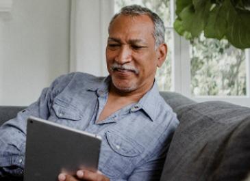 A man smiles as he scrolls on his iPad