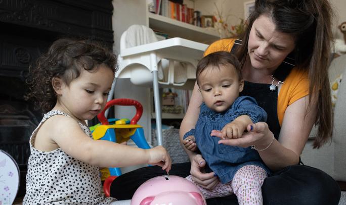 A woman and two children play together with a piggy bank