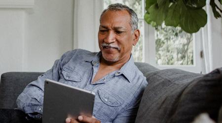 A man smiles as he scrolls on his iPad